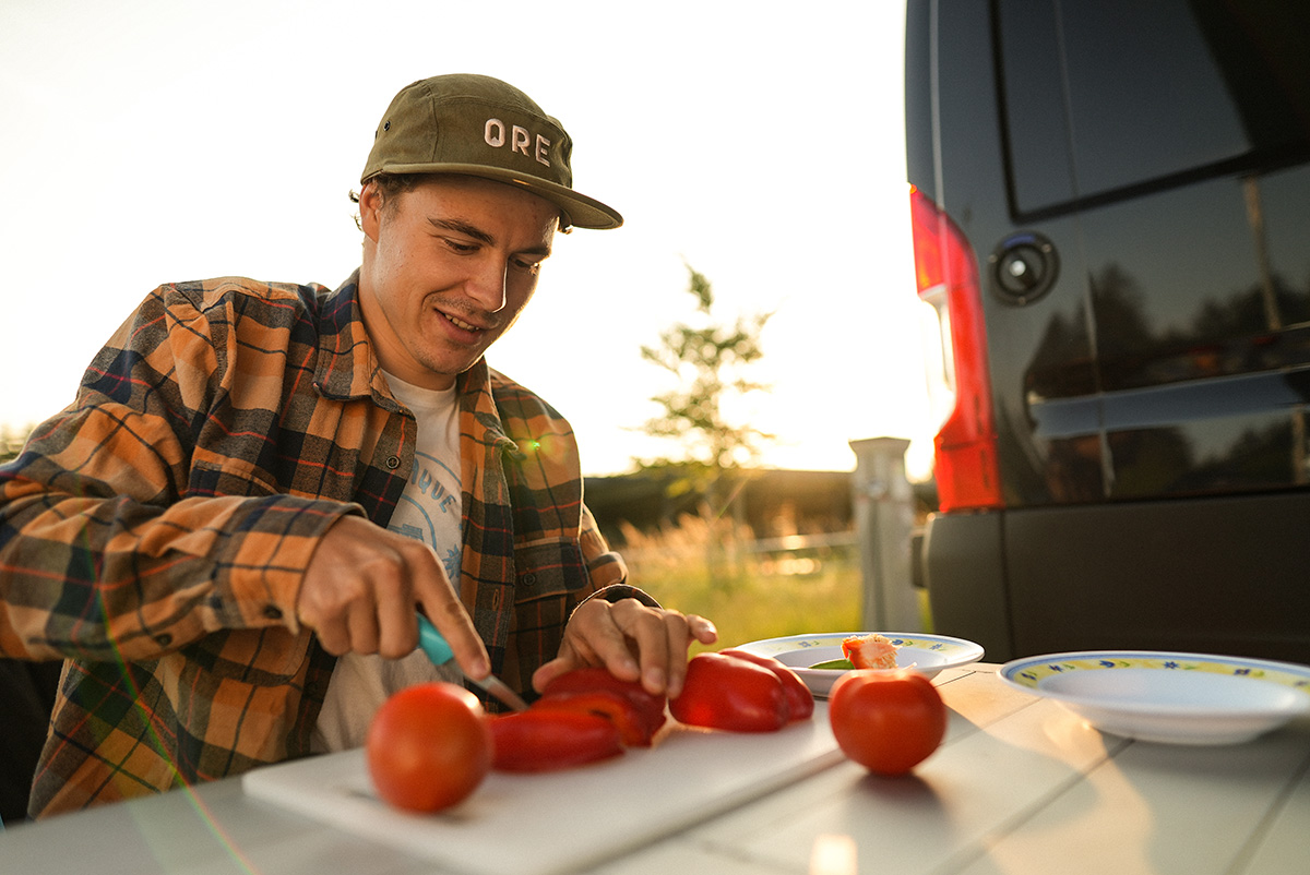 Ruben schneidet Tomate am Wohnmobil